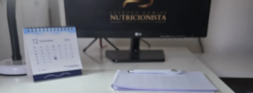 Mesa do consultório com o logo Leandro Gomide Nutricionista na tela do computador
